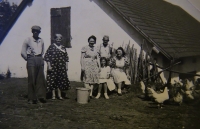 On her grandfather's yard in Třepšín, Naďa sitting in the middle, her aunt on the right, her mother on the left, grandfather standing above her, 1942 