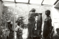 Marie Uchytilová na štaflích zakrývá mokrým hadrem sochu velké dívky z hlíny (r. 1988)