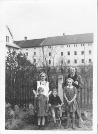 František Křížek (in a coat on the left) with his family in front of his house and the fence over which flour was smuggled from Bartoš's mill (in the background), photographed at the end of the 1930s