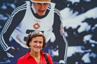 Květa Jeriová Pecková posing in front of a large foramt photo from the Olympics in Sarajevo 