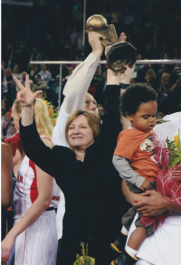 Natália Hejková is holding the EuroLeague Women cup above her head; her team has won