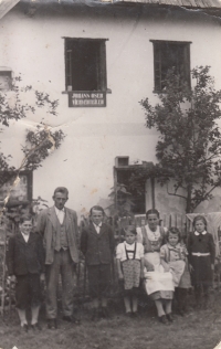 Oser family (from the left: Johann jr., father Johann, Hermann, Emma, mother Johanna, Helge, Mathilde) in front of their house in Hutsky Dvur,  Sumava. Sign on the house "Johann Oser Viehverteiler", 1944