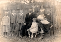 A family photo from 1935, Marie Henzlová sitting on a chair in front of her parents 
