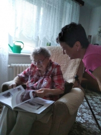 Růžena Vavřichová listuje knihou a vzpomíná pod laskavým dohledem své pečovatelky Lenky Vracovské.