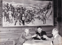 Karel Kodejška (centre) in the ski clubroom in Lomnice nad Popelkou, there is a picture of the local ski resort hanging above him