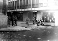 Milicionáři zasahující u „Centrumu“ v Brně při demonstracích v roce 1969 – sehnutá prchající postava je milicionář, který dostal dlažební kostkou do hlavy, na chodníku leží jeho čepice