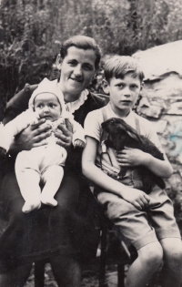 A guardian Hedvika Vařbuchtová, holds Gertrude on her lap and Gertrude's half-brother Stanislav sits next to her, 1944
