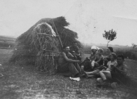 Žně. Pamětnice (druhá zprava) s rodinou odpočívající u mandele, asi 1945