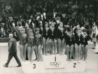 The podium at the 1968 Olympics. The Czechoslovak team finished second behind the Soviet sportswomen. Bohumila Řešátková is standing second from the right and waving to the spectators