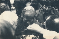 Particularly well-taken picture of Václav Havel in a crowd of visitors of the Folk Lipnice festival signing autographs while bemused Viktor Púčala, a member of the district State Security, is looking over his shoulder, September 1988