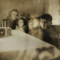 Children at the table in the agricultural building of Josef Mareš. On the photograph is Marie Marešová on the occasion of the birthday of her two-year-old daughter Marie. First from the right sits the son of the evicted farmer Markvart from Obrataně, Hlasivo 