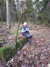 Karin Nováková sitting on the remains of her native house’s door yard, Ermesgrün (Smrčina) 1, 2022