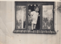 At the age of two in the window of the apartment in the house in Schnellau (Slané) where her family lived with her paternal grandparents, the 1930s