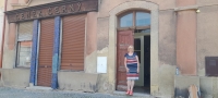 Marie Vladyková in front of her house, 2023. On the house is the original shield of the butcher Čeněk Černý