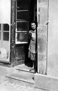 Anna Marková's mother in the doorway of a house with a shop and glassworks in Vrbno pod Pradědem