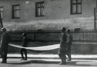 Parade through Uhlířov during a firemen's festival in 1964. The firefighters carry the Czechoslovak flag in front of the former manor farm office building, which at the time housed a Jednota grocery shop and a community centre