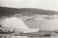 Filling of the Josefův Důl Waterworks Reservoir. In the picture - the main dam with the shaft overflow, the footbridge to the combined building and in the background the objects of the construction site equipment, around 1981
