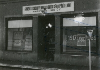 Pohled na vchod do kanceláře sekretariátu OV SČSP z ulice Lužické v Novém Jičíně. Skleněná tabule vývěsního štítu je rozbita a dveře jsou potřísněné červenou barvou. Fotografie ze spisu V-4629 OV, důkazní materiál nasbíraný StB