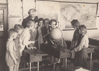Mrs. Čejková in 1954 with her pupils at the school in Jičíněves. Wintess bending over the globe