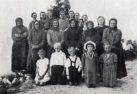 A group of women and children from Malín who survived the raid. Mstislav Pospíšil is standing in the middle of the first row.