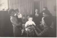 Zsuzsanna Gyenes (in a chequer tucker) holds a cake to her son András in 1965, the family around