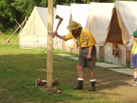 Start of a camp day - the leader who is on duty is driving the axe into a log under the pole, Dědov, the present day 